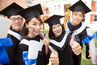 Group of graduating students holding diploma and thumb-up 