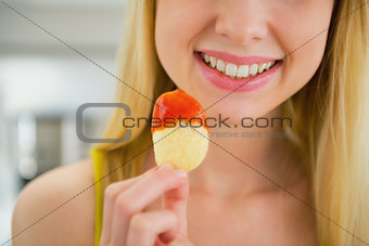 Closeup on young woman eating chips