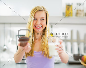 Young woman showing chocolate muffin and milk