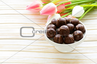 chocolate candy and flowers on wooden background