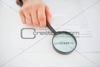 Closeup on business woman holding magnifying glass in front of i