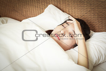 woman lying on bed with Migraine