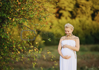 beautiful pregnant young woman in greek white dress outside