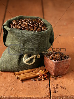 Still life of coffee beans in canvas sack on vintage wooden background