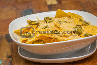 Nachos with cheese and jalapenos in a white bowl