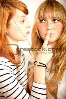 red haired and blond girl sign to shut up