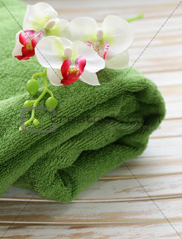 green towel and orchid flowers on a wooden background