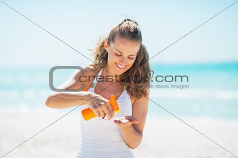 Happy young woman on beach applying sun screen creme