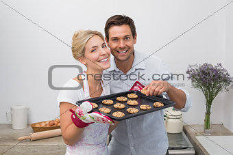 Portrait of couple with freshly baked cookies in kitchen