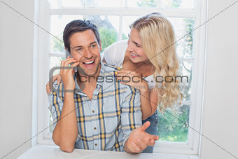 Happy man on call besides a woman at home