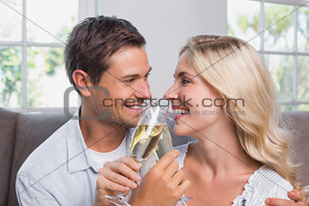 Cheerful loving couple with champagne flutes at home