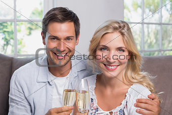 Cheerful young couple with champagne flutes at home