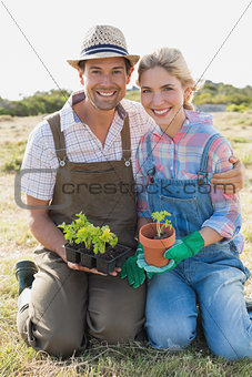 Smiling couple with potted plants in field