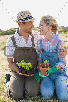 Smiling couple with potted plants in the field