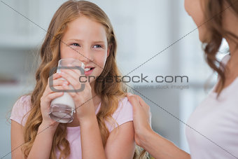 Cute girl drinking milk as she looks to her mother