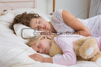 Girl and mother sleeping with stuffed toy in bed