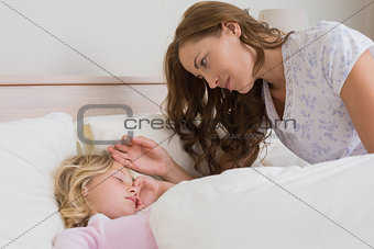 Mother watching girl as she sleeps peacefully in bed