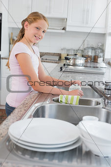 Portrait of a girl washing utensils in kitchen