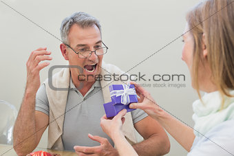 Shocked man receiving gift by woman