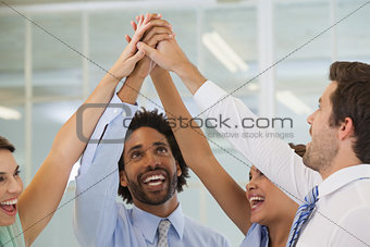 Cheerful business team joining hands together in office