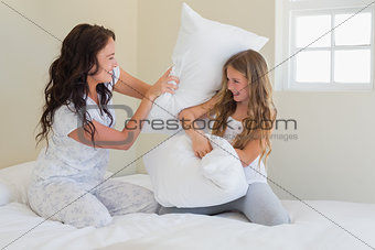 Mother and daughter having pillow fight in bed