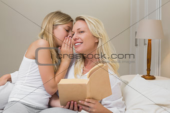 Girl sharing secrets with mother in bed