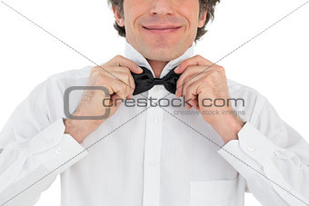 Happy groom adjusting bow tie