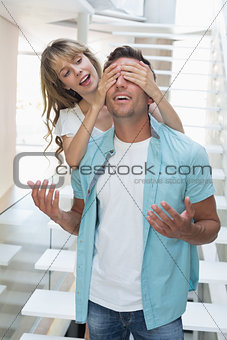 woman covering happy mans eyes