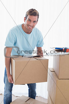 Smiling man with cardboard boxes in new house