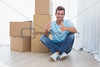 Man gesturing thumbs up with cardboard boxes in new house