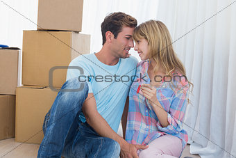 Couple holding new house key against cardboard boxes