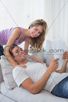 Relaxed young couple reading document on couch