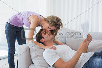 Woman kissing mans forehead while he reads document