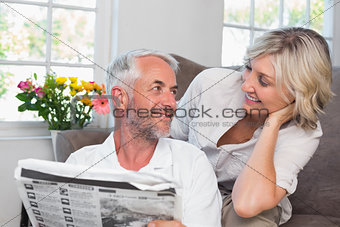 Couple looking at each other while reading newspaper
