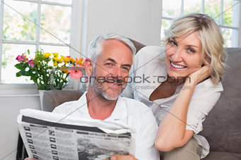 Happy mature couple reading newspaper at home