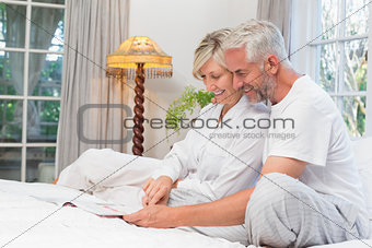 Relaxed mature couple reading book in bed