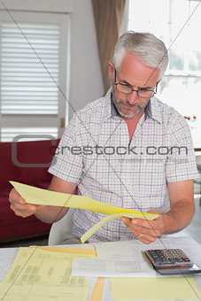 Serious mature man with home bills and calculator
