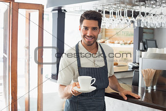Waiter holding cup of coffee at café