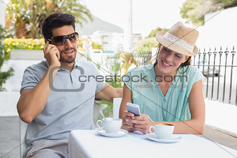 Happy couple with mobile phones at coffee shop