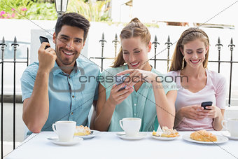 Happy friends reading text message in café