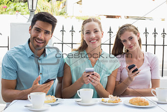 Happy friends reading text message in café