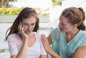 Woman consoling a friend while shes on call in café
