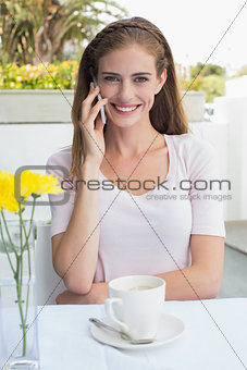 Woman with coffee cup using mobile phone in café
