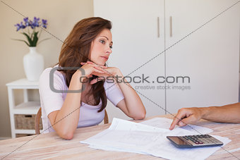 Angry young woman with hand pointing at home bills