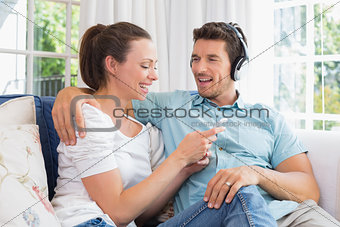 Couple listening music with mobile phone on couch