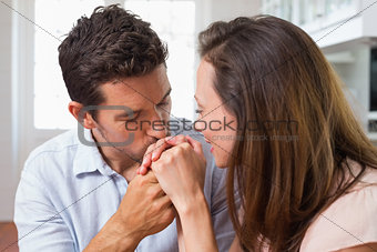 Loving man kissing womans hand at home