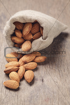 small sack bag full of almonds on wooden table