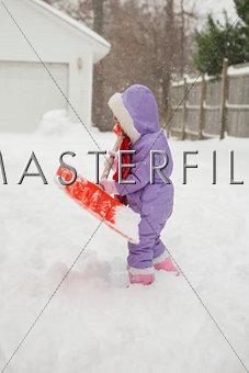 Toddler girl shoveling snow