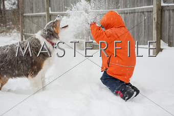 Boy having a snowball fight with his dog
