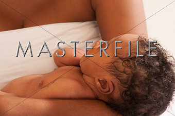 Sleeping African American newborn baby cradled in mother's arms